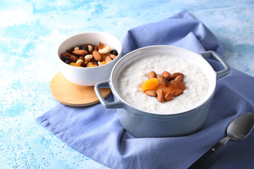 Delicious rice pudding with dried apricots and almonds in casserole on table