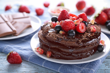 Plate with tasty chocolate pancakes and berries on table, closeup