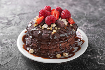 Plate with tasty chocolate pancakes and berries on grunge table
