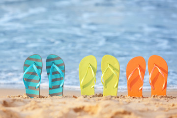 Fototapeta premium Set of beach flip-flops on sand near sea