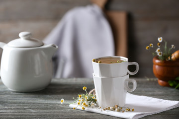 Cups of delicious chamomile tea on wooden table