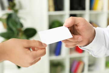 Man giving business card to woman in office, closeup