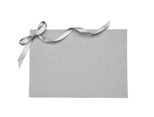 Blank paper card with silver ribbon and bow on white background