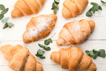 Tasty croissants on light wooden table