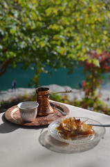 Baklava from Bosnia is a rich, sweet dessert pastry made of layers of filo filled with chopped nuts and sweetened and held together with syrup. And behind is a traditional turkish coffee.