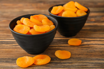Bowl with dried apricots on wooden table