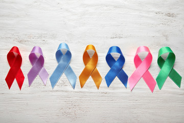 Different colorful ribbons on white wooden background. Cancer concept