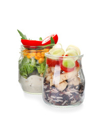 Fototapeta na wymiar Delicious vegetable salads with chicken in mason jars on white background