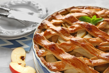 Dish with delicious apple pie on table