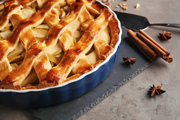 Dish with delicious apple pie on grey table