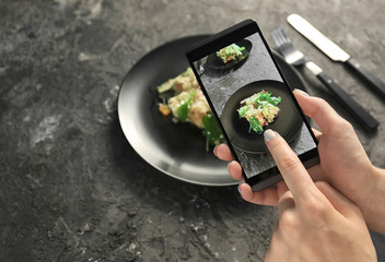 Woman taking photo of healthy salad with mobile phone, closeup
