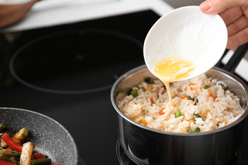 Pouring of melted butter into saucepan with boiled rice and vegetables in kitchen
