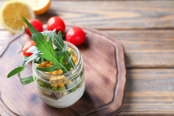 Delicious vegetable salad with chicken in mason jar on wooden board