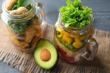 Delicious vegetable salads in mason jars on wooden table