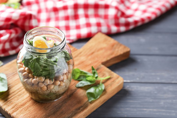 Delicious vegetable salad in mason jar on wooden board