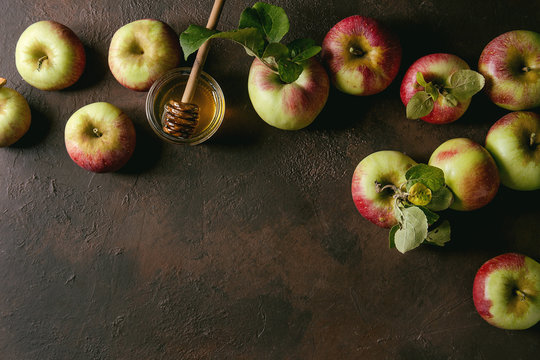 Ripe organic gardening green red apples with leaves and jar of honey over dark texture background. Flat lay, space. Autumn harvest