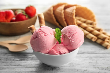 Bowl with delicious strawberry ice-cream and wafer sticks on wooden background