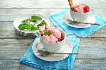 Cups with delicious strawberry ice-cream on wooden background