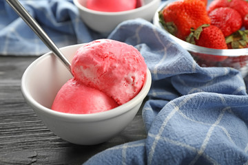 Bowl with delicious strawberry ice-cream on wooden background, closeup