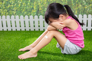 Asian Little Chinese girl sitting on the grass and crying