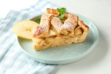 Plate with piece of delicious apple pie on white table, closeup