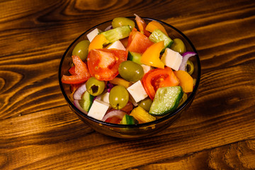 Glass bowl with greek salad on wooden table