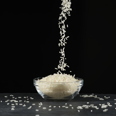 Arroz cayendo en un bol sobre fondo negro