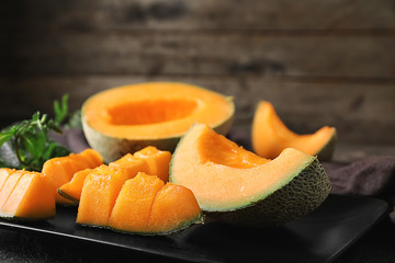 Plate with tasty cut melon on table