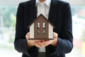 Real estate agent with house model indoors