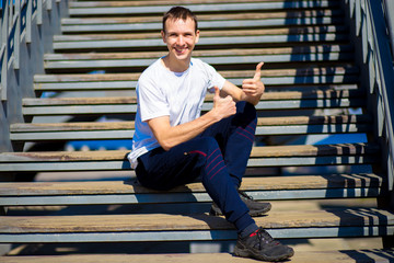 Young man on stairs in sunny day. Street style