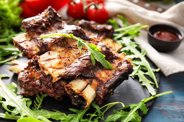 Delicious grilled ribs with arugula on slate plate