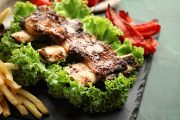 Delicious grilled ribs with vegetables and french fries on slate plate