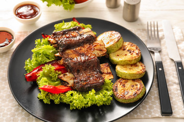 Delicious grilled ribs with vegetables on plate