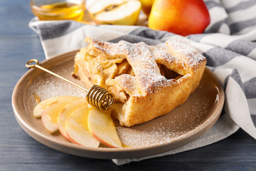 Plate with piece of delicious apple pie on wooden table, closeup