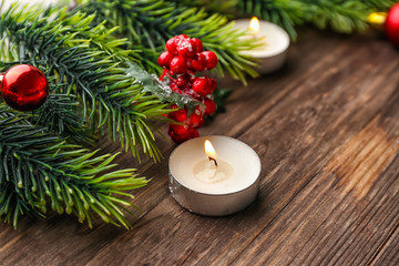 Burning candle with Christmas tree branches on wooden background