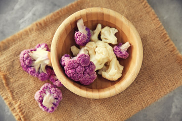 Fototapeta na wymiar Bowl with colorful cauliflowers on table