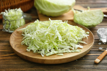 Plate with cut cabbage on wooden table, closeup