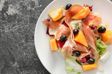 Delicious salad with melon and prosciutto on plate