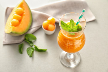 Glass of fresh melon smoothie on light table