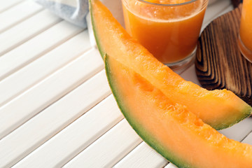 Slices of ripe melon with glass of fresh smoothie on white table
