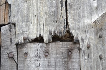 Closeup photograph of gray weathered planks in a barn door.