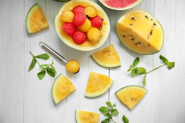 Delicious cut watermelons with balls on white wooden table
