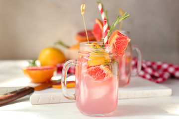 Fresh grapefruit cocktail with rosemary in mason jar on light table