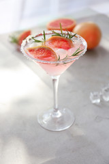 Fresh grapefruit cocktail with rosemary in glass on light table