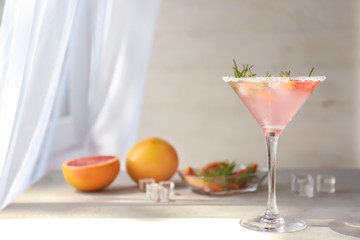 Fresh grapefruit cocktail with rosemary in glass on light table