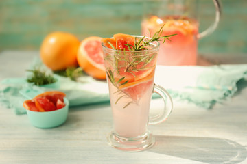 Fresh grapefruit cocktail with rosemary in glass cup on white table