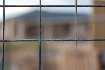 A wire fence with a selectively blurred background of a housing development in South Australia on 29th August 2018