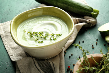 Tasty zucchini soup in bowl on color table