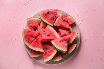 Plate with slices of ripe watermelon on color background