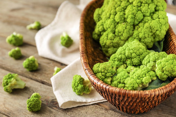 Basket with green cauliflower cabbage on wooden table, closeup